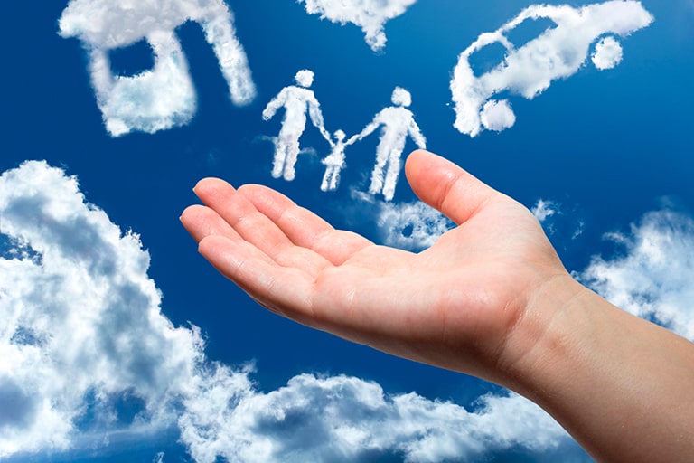 Imagem de uma mão e ao fundo, um céu com nuvens em formato de família, casa e um carro